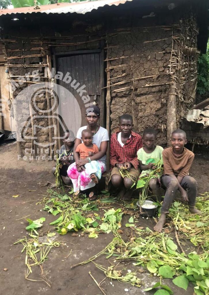 family seated in front of their door house.